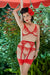 Model wearing Lavinia Flame Plunge Bra set by Dita Von Teese outdoors, highlighting retro glamour with red lace, garter belt, and sheer stockings.